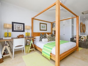 Un dormitorio con cama con dosel, un escritorio con silla y un sofá.