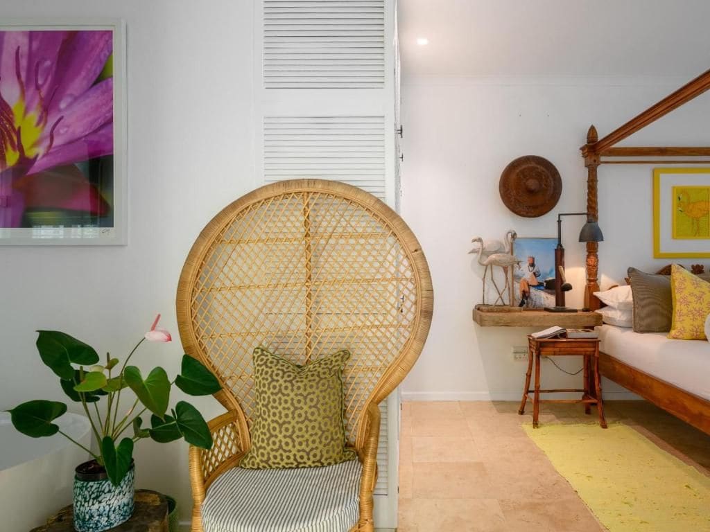 Quarto com cadeira de vime, sofá, planta em vaso e quadro na parede.