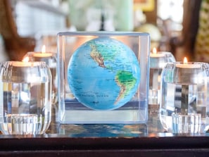 A globe encased in a transparent square frame, surrounded by lit candles.