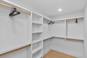 Ein begehbarer Kleiderschrank mit mehreren Regalen und Kleiderstangen.