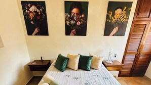 Een hotelkamer met een bed, kussens, een nachtkastje, een lamp en decoratie aan de muur.