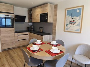 A modern kitchen with built-in appliances, a dining table set for four with red placemats, and a framed picture on the wall. - 200m from ski slopes, 2nd floor, terrace, tv, ski locker, 36m², Champagny-en-Vanoise (Champagny-en-Vanoise)