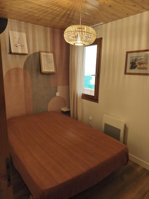 A bedroom with a wooden bed, a window with curtains, and framed pictures on the walls. - 200m from ski slopes, 2nd floor, terrace, tv, ski locker, 36m², Champagny-en-Vanoise (Champagny-en-Vanoise)