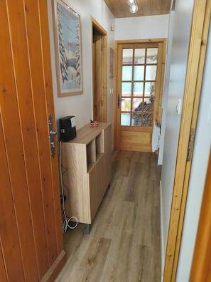 A narrow hallway with wooden flooring, a wooden door with glass panels, and a small table with a kettle. - 200m from ski slopes, 2nd floor, terrace, tv, ski locker, 36m², Champagny-en-Vanoise (Champagny-en-Vanoise)