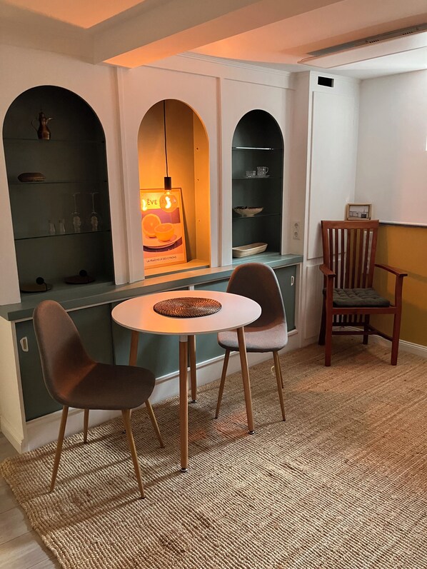 Cocina pequeña con una mesa redonda, dos sillas y una silla de madera.
