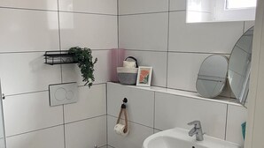 Casa de banho moderna com sanita, lavatório e espelho.
