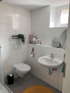 Un baño moderno con inodoro, lavamanos y espejo.