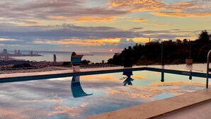 A swimming pool with a view of a city skyline and sunset. - Villa With a Panoramic Bathtub and Pool Overlooking a Beautiful View of Batumi (kapreshumi)