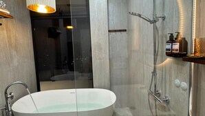 A modern bathroom with a freestanding bathtub, a glass-enclosed shower, and a vanity with toiletries. - Villa With a Panoramic Bathtub and Pool Overlooking a Beautiful View of Batumi (kapreshumi)