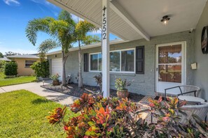 A residential property with a covered porch, a garage, and a patio area with outdoor furniture. - Seacrest Bungalow - Cozy, Family, Beach @ 10 min (Largo)