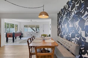 A dining area with a wooden table, chairs, and a hanging pendant light. - Seacrest Bungalow - Cozy, Family, Beach @ 10 min (Largo)