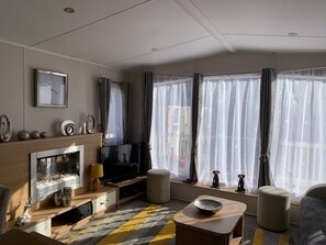 A modern living room with a fireplace, television, and seating area. - Cayton Bay Caravan Park - Holiday Accommodation 11337 (Scarborough)