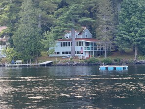 A house by a lake with a dock and a boat. - Maranacook Lake Cabin: 3BR+detached bunkhouse, Porch,summer Dock on .5 Acre. (Winthrop)