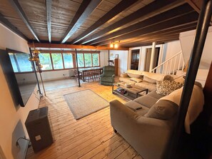 Ein geräumiges Wohnzimmer mit Holzboden, einer Couch, einem Couchtisch und einem Essbereich mit Tisch und Stühlen.