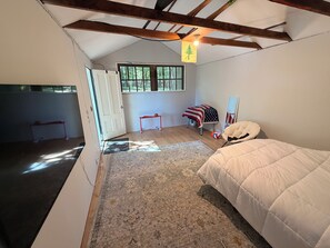 Ein Schlafzimmer mit einem Bett, einem kleinen Basketballkorb, einem Teppich und einem Fenster mit Blick auf Bäume.