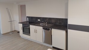 Una cocina moderna con horno empotrado, lavavajillas y pileta de acero inoxidable.