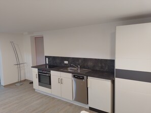 Cozinha moderna com forno embutido, máquina de lavar louça e pia de aço inoxidável.