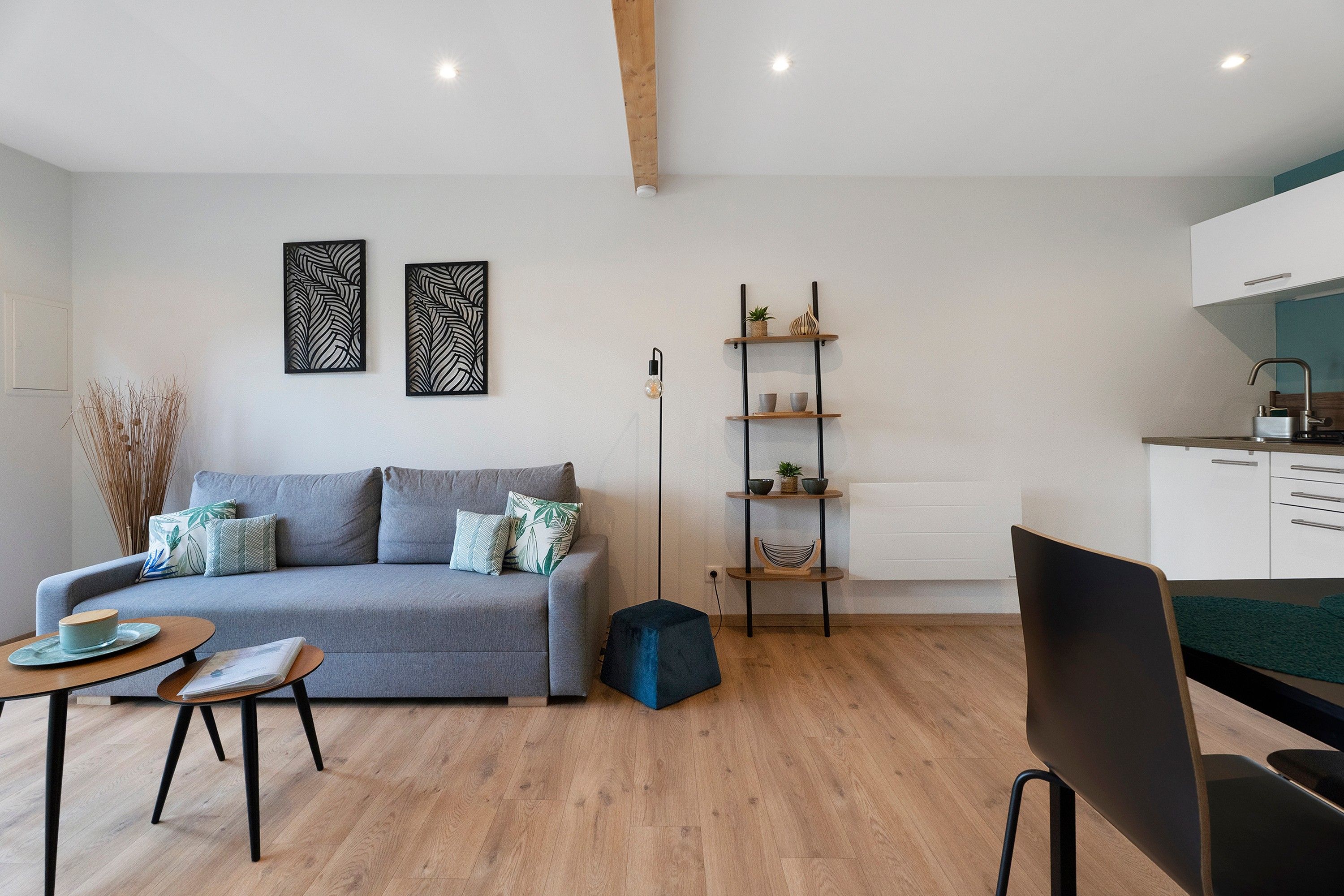 A modern living room with a grey sofa, a coffee table, and a bookshelf.