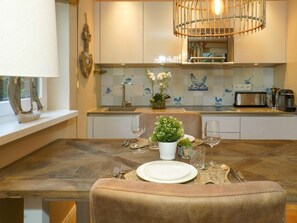 A dining area with a wooden table, white plates, and a vase of flowers. - Apartment in Westerland With Swimming Pool (Sylt)