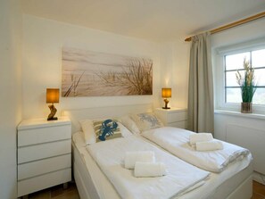 Ein Hotelzimmer mit einem Bett, zwei Nachttischen, einem Fenster mit Blick und einem an der Wand hängenden Kunstwerk.