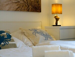 A neatly made bed with a decorative pillow, a bedside lamp, and a wall-mounted artwork. - Apartment in Westerland With Swimming Pool (Sylt)