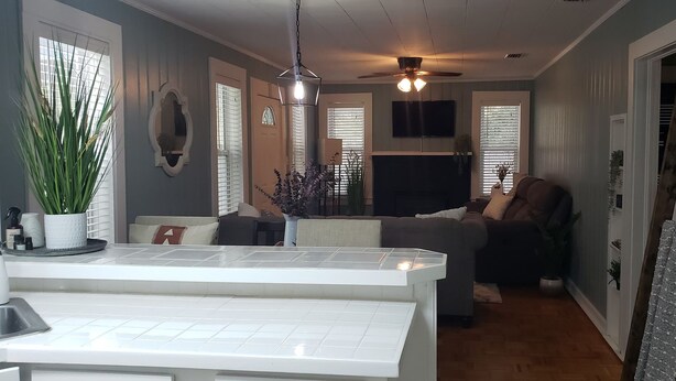 A modern kitchen with a central island, a dining area with a sofa, and a ceiling fan. - Three Rivers Retreat (Lake City)