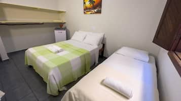 A room with two beds, a small desk, and a wall-mounted shelf.