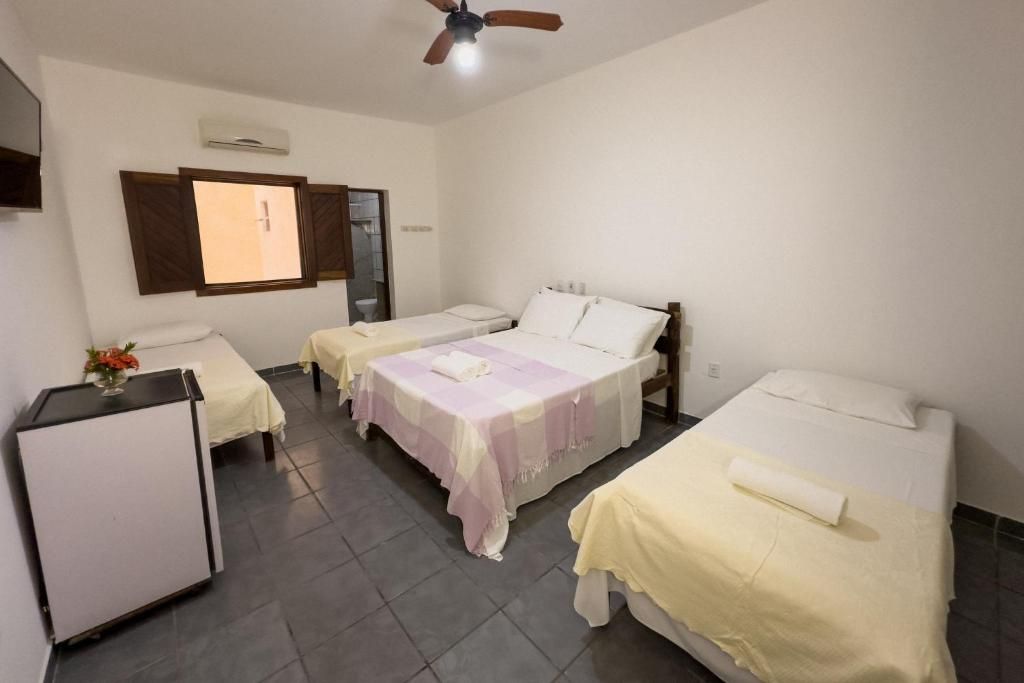 Ein Hotelzimmer mit zwei Einzelbetten, einem kleinen Schreibtisch und einem Deckenventilator.
