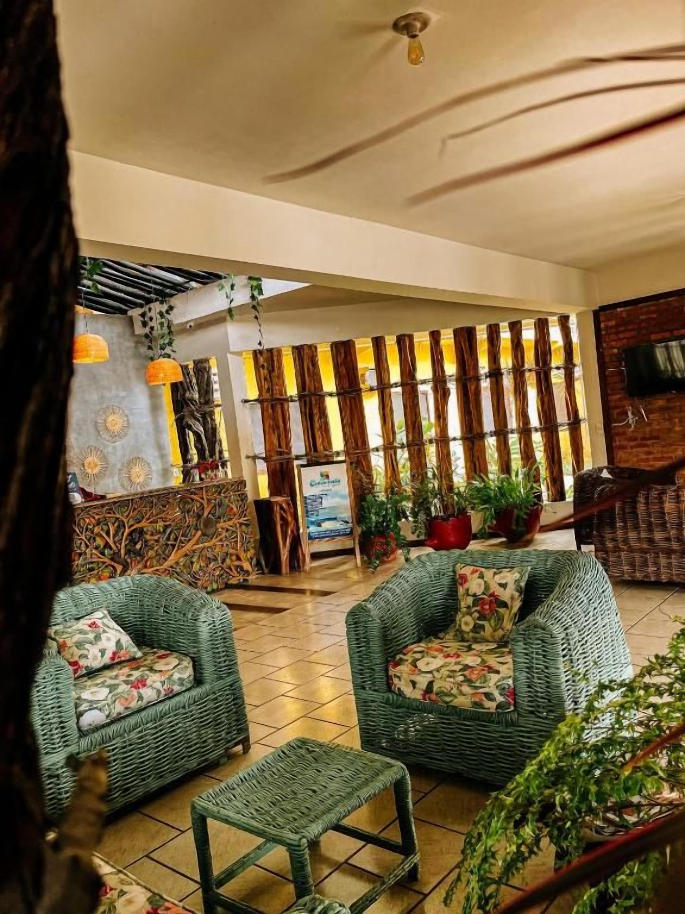 A lobby with wicker furniture, a reception desk, and potted plants.