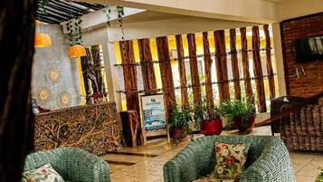 A lobby with wicker furniture, a reception desk, and potted plants.