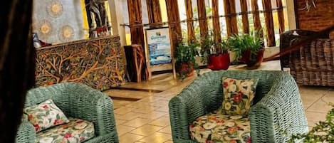 A lobby with wicker furniture, a reception desk, and potted plants.