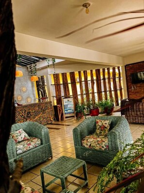 A lobby with wicker furniture, a reception desk, and potted plants.