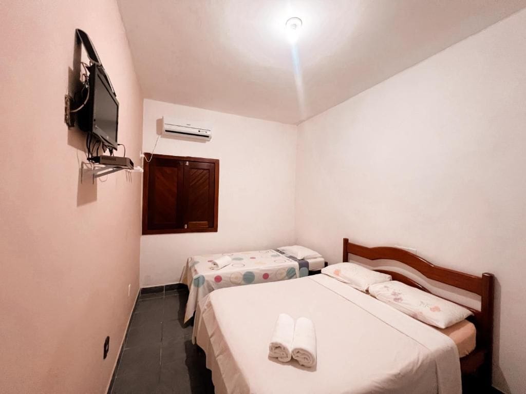 Una habitación de hotel pequeña con dos camas, un televisor, un equipo de aire acondicionado y una puerta de madera.