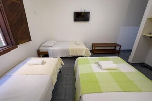 A room with two beds, a television on the wall, and a small wooden table.