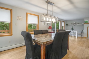 A dining area with a wooden table, four chairs, and a hanging light fixture.