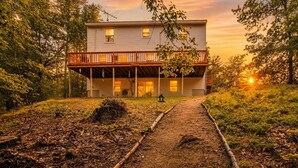 A two-story house with a porch and a pathway leading to the entrance.