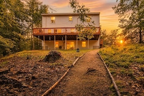 A two-story house with a porch and a pathway leading to the entrance.