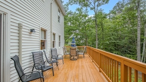 A wooden deck with outdoor furniture and a view of a forest.