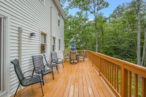 A wooden deck with outdoor furniture and a view of a forest.