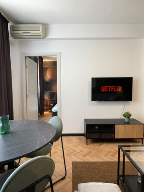 A modern living room with a flat-screen TV mounted on the wall, a dining table with chairs, and a small cabinet. - Chill Flow Calea Victoriei next to The Old Town (București)