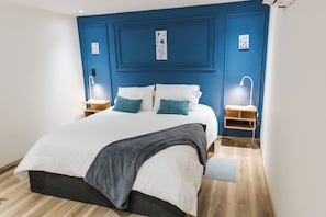 Ein Schlafzimmer mit einem Bett, Nachttischen, Lampen und einer blauen Akzentwand.