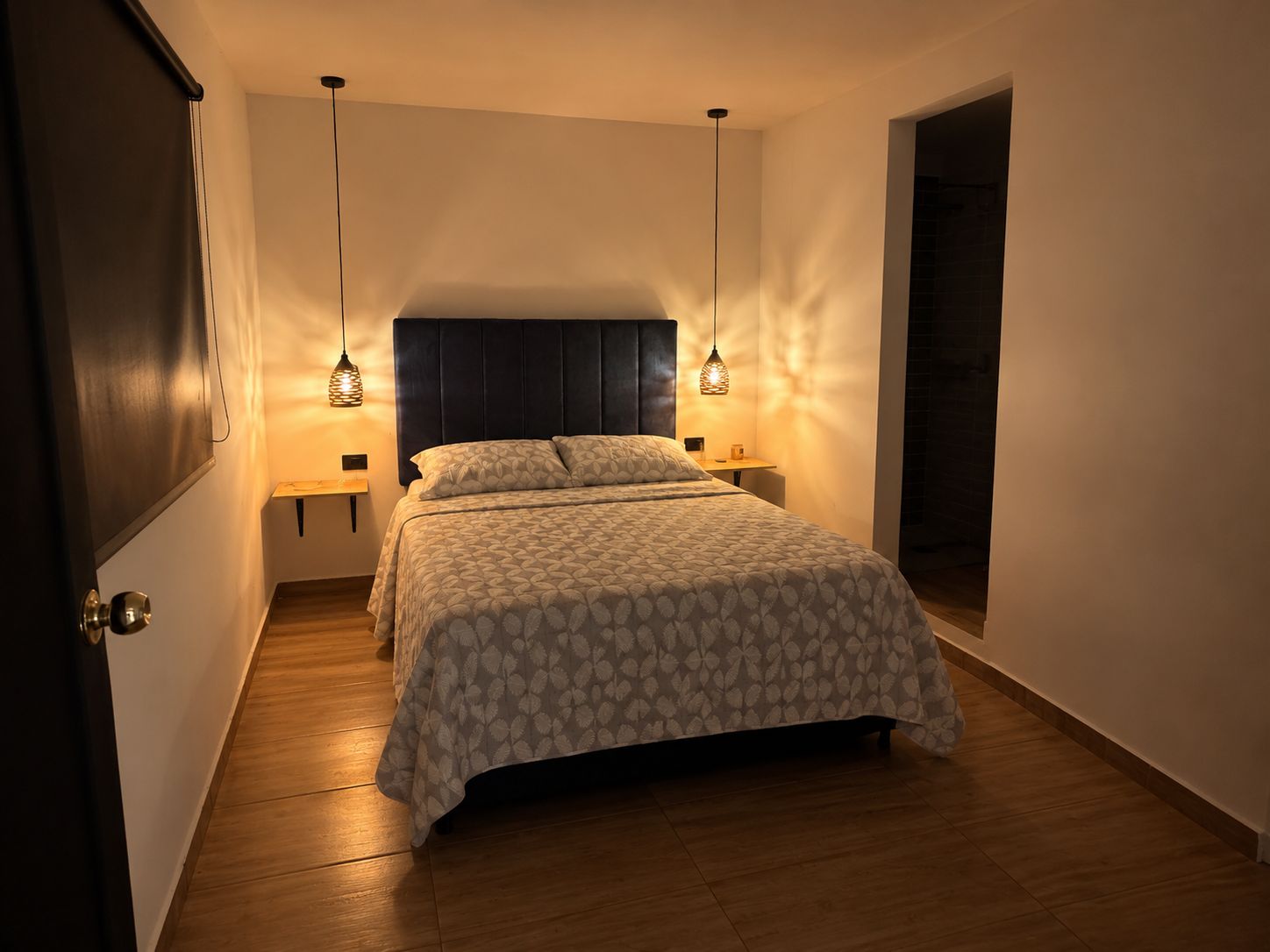 Une chambre à coucher avec un lit, des tables de chevet et des lampes suspendues.