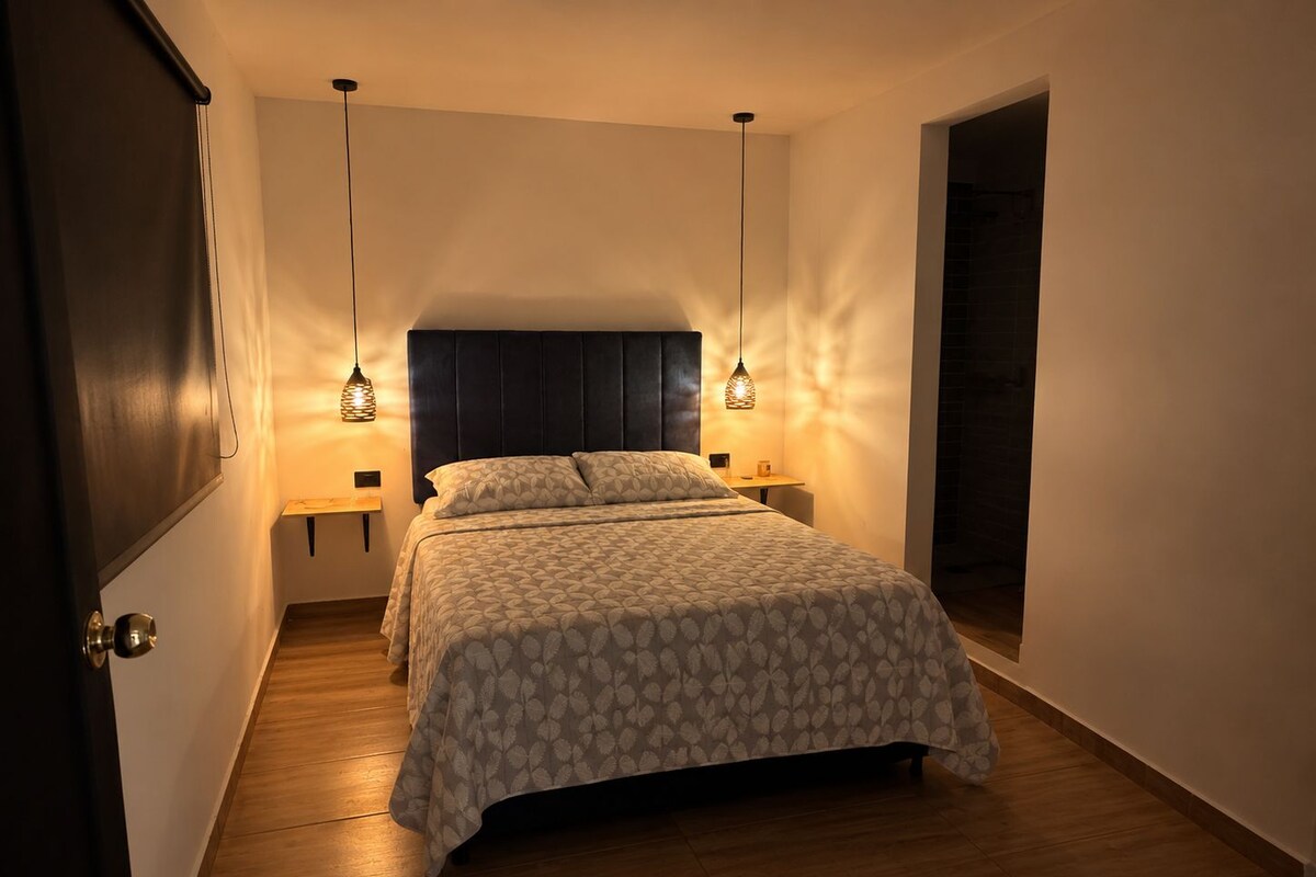 A bedroom with a bed, bedside tables, and hanging lamps.
