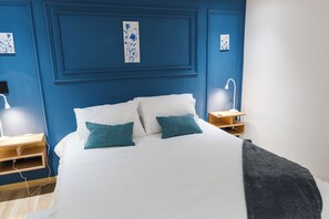 Ein Schlafzimmer mit einem Bett, zwei Kissen, einem Nachttisch, einer Lampe und einem Wandregal.