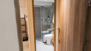 A modern bathroom with a glass shower enclosure, a white toilet, and a wooden vanity. - Hotel 664 (Poblado)