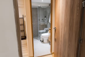 Ein modernes Badezimmer mit Duschabtrennung aus Glas, einer weißen Toilette und einem Holz-Waschtisch.
