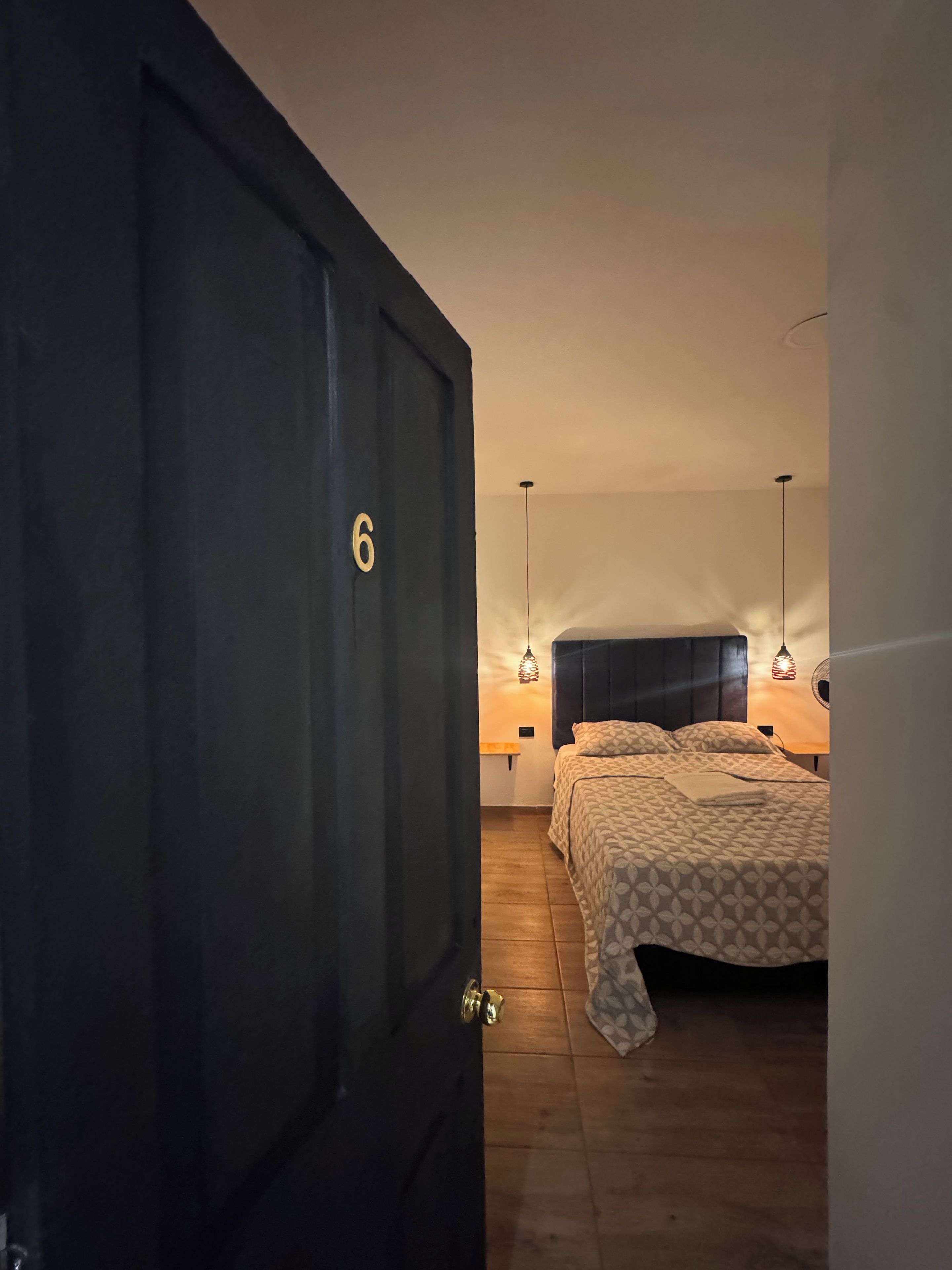 A bedroom with a large bed, a wooden floor, and a door with a number.