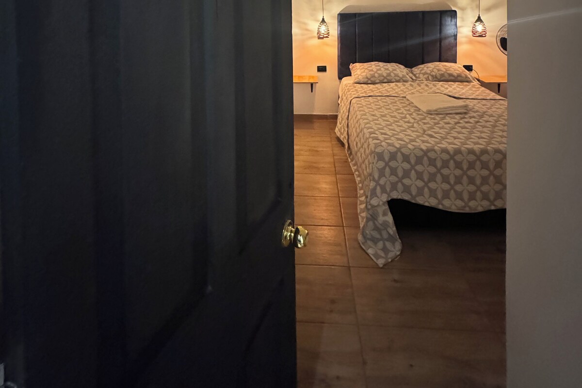 A bedroom with a large bed, a wooden floor, and a door with a number.