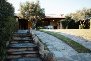 A stone staircase leading to a building with a tiled roof, surrounded by well-maintained grass and trees. - Villetta Rosella by Wonderful Italy (Golfo Aranci)