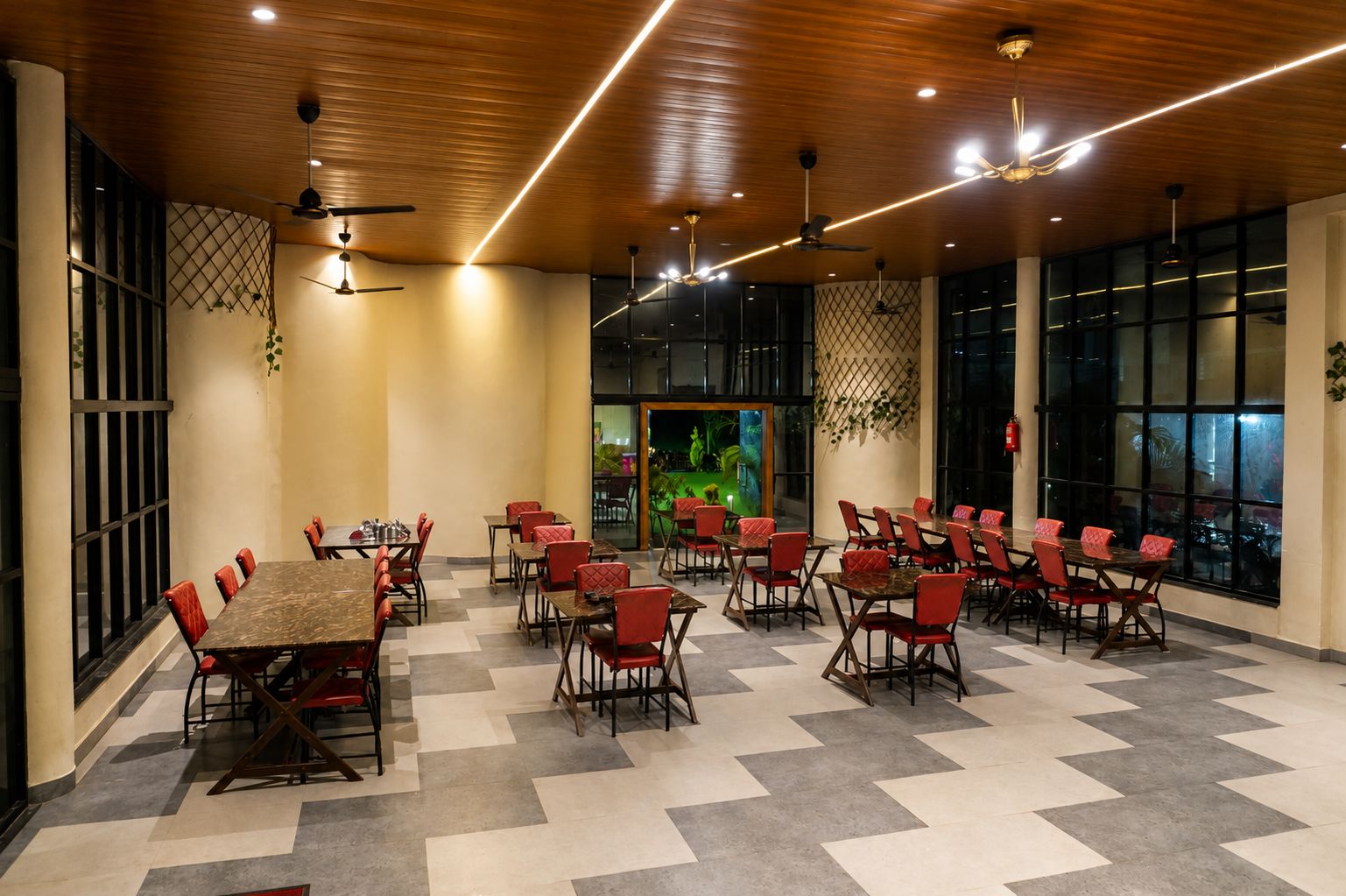 Un vaste espace de restauration intérieur, doté de nombreuses tables et chaises, de ventilateurs de plafond et de grandes fenêtres.